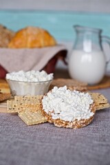 Obraz na płótnie Canvas A small plate of ricotta with crispbreads, oat bread, healthy food, on the wooden cutting board, milk jug 