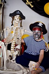 Young boy 7- 9 year old dressed as a pirate sitting on the floor with the pirate skeleton