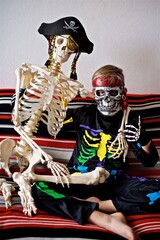 Young boy 7- 9 year old dressed as a colourful skeleton sitting on the sofa with the pirate...
