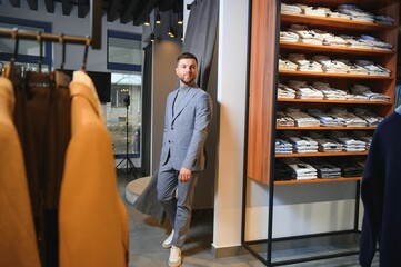 Modern young handsome businessman, looking and choosing classical suit in the suit shop