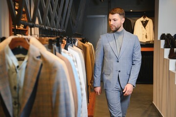 Businessman in classic vest against row of suits in shop