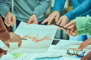 Individuals examining and discussing a complex data visualization sheet among other graphs. Collages working with analytical graphs. Concept of business, teamwork, modern office