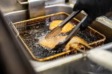 Chef cooking delicious potato hash browns in hot oil on kitchen - obrazy, fototapety, plakaty