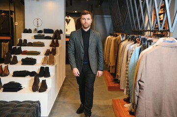 Fototapeta na wymiar Businessman in classic vest against row of suits in shop