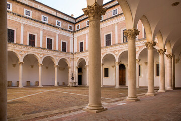 Obraz premium Internal courtyard of the ducal palace of Urbino, in the Marche region, Italy. The square is empty and there is no one in this ancient building, legacy of the Italian Renaissance.