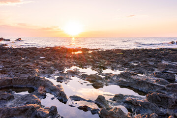 beautiful golden sunset or sunrise on a seashore bank with blue sea water and yellow sunnny evening cloudy sky
