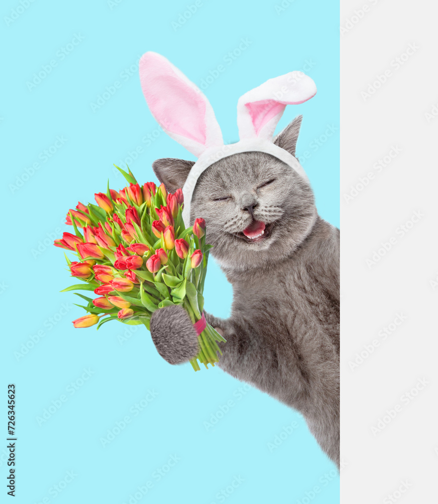 Aufkleber happy kitten wearing easter rabbits ears holds holds bouquet of tulips and looks from behind empty w