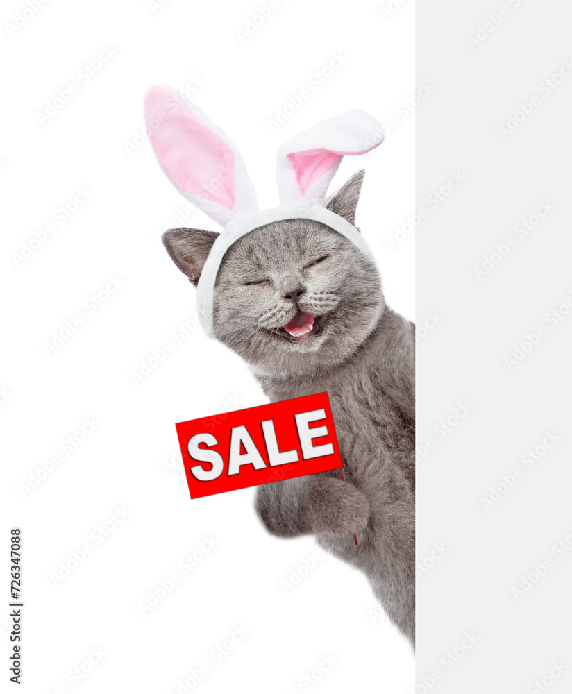 Poster laughing cat wearing easter rabbits ears holds sales symbol behind empty white banner. isolated on w
