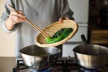 茹で上がったほうれん草をざるにあげるところ