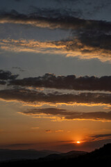 Fototapeta premium Beautiful sunset in the mountains. Sunset View from the Top of a Mountain. Sunset in strong orange tones in Serbia. The sun falls for horizon, a sunset. Shadows are condensed, beautiful clouds. 