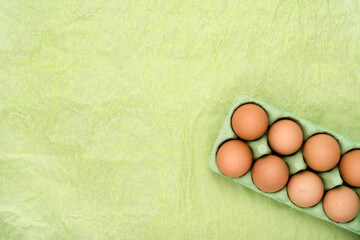 Green carton of different shade eggs on wrinkled background. Copy space simple pastel rustic background for traditional Easter holiday card