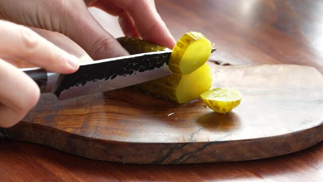 Zoom on woman hand cutting pickles on wooden table. Slow motion. High quality 4k footage