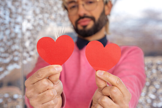  portrait smiling young man holding hearts on Valentine's Day outdoors.