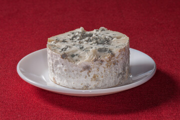 Fromage bleu dans une petite assiette blanche posée sur une nappe rouge