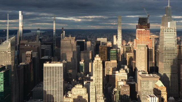 Aerial timelapse of midtown Manhattan buildings and supertall skyscrapers. Dramatically illuminated New York City skyline with passing clouds