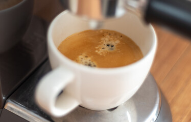 Wonderful espresso shot pouring out. Home coffee machine to make espresso in to the white cup.