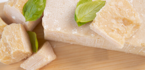 Slices of parmesan cheese, close-up. grano padano cheese with fresh green basil leaves