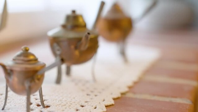 Antique brass teapots rest on a delicate lace doily over a rustic wooden table invoking nostalgia and warmth