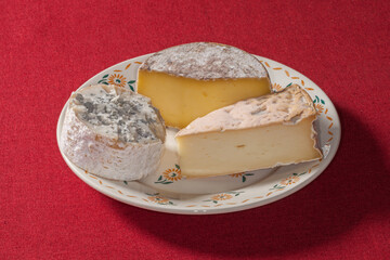 Trois fromages entamés posés dans une petite assiette blanche