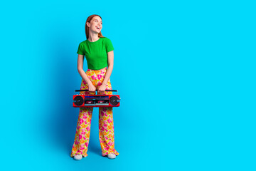 Full size photo of nice girl wear stylish top hold retro boombox look at event announcement empty space isolated on blue color background