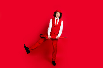 Full body length photo of elegant teenager in stylish suit with parasol makes boogie woogie simple dance isolated on red color background