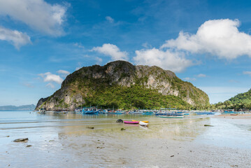 El Nido Seashore in Palawan. Low Tide and Mountain with Boats in Background. Sandy Beach.