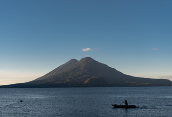 Fototapeta na wymiar Man in Boat and Atitlan Lake in Guatemala. Long Exposure. Volcano in Background. Morning Light.