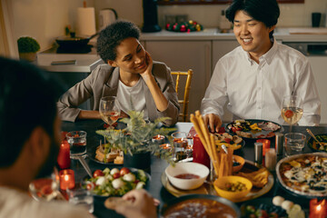 Group of smiling friends enjoying in conversation during Christmas party at home
