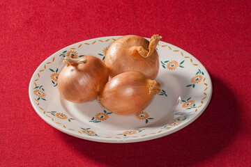 Trois oignons posés dans une assiette