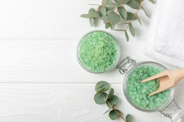 Cosmetic sea salt with aroma and eucalyptus extract on a textured wooden background with branches...