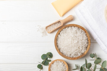 Cosmetic sea salt with aroma and eucalyptus extract on a textured wooden background with branches of fresh aromatic eucalyptus.Spa concept. Bath salt. Close-up. Space for text.Body care.copy space