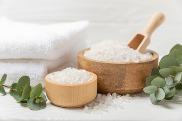 Cosmetic sea salt with aroma and eucalyptus extract on a textured wooden background with branches of fresh aromatic eucalyptus.Spa concept. Bath salt. Close-up. Space for text.Body care.copy space