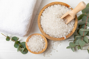 Fototapeta na wymiar Cosmetic sea salt with aroma and eucalyptus extract on a textured wooden background with branches of fresh aromatic eucalyptus.Spa concept. Bath salt. Close-up. Space for text.Body care.copy space