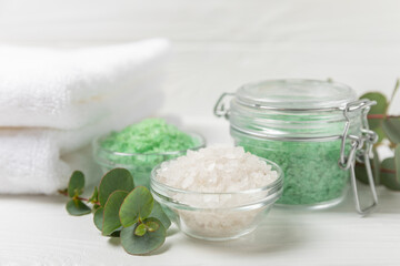 Cosmetic sea salt with aroma and eucalyptus extract on a textured wooden background with branches of fresh aromatic eucalyptus.Spa concept. Bath salt. Close-up. Space for text.Body care.copy space