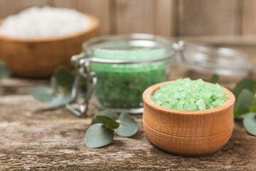 Cosmetic sea salt with aroma and eucalyptus extract on a textured wooden background with branches of fresh aromatic eucalyptus.Spa concept. Bath salt. Close-up. Space for text.Body care.copy space
