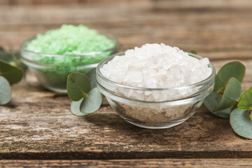 Cosmetic sea salt with aroma and eucalyptus extract on a textured wooden background with branches of fresh aromatic eucalyptus.Spa concept. Bath salt. Close-up. Space for text.Body care.copy space