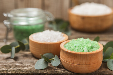 Cosmetic sea salt with aroma and eucalyptus extract on a textured wooden background with branches of fresh aromatic eucalyptus.Spa concept. Bath salt. Close-up. Space for text.Body care.copy space