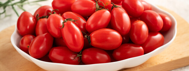 Fresh cherry tomatoes over white table background.