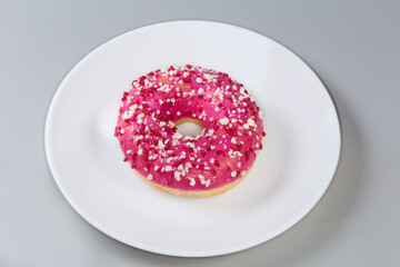 Doughnut with raspberry filling, pink glaze and sprinkles on dish