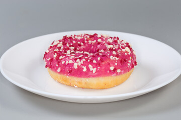 Doughnut with raspberry filling, pink glaze and sprinkles close-up