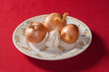 Trois oignons et une gousse d'ail posés dans une assiette