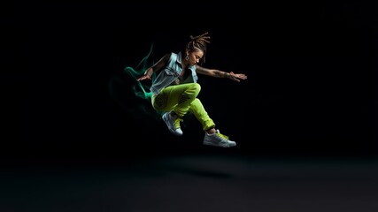 Dance in Flight, An energetic leap frozen in silhouette, embodying the spirit of a passionate hip-hop performance on a vivid saturated green neon background. Generative AI.