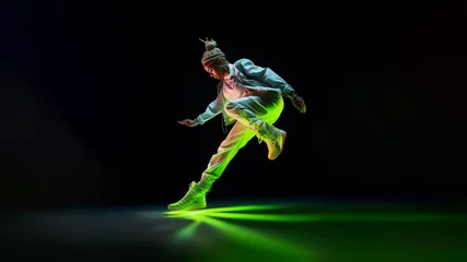 Fotobehang Dance in Flight, An energetic leap frozen in silhouette, embodying the spirit of a passionate hip-hop performance on a vivid saturated green neon background. Generative AI. © Surachetsh