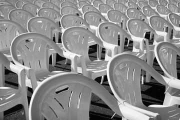 Empty white chairs in a row, outdoor event.