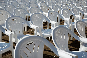 Empty white chairs in a row, outdoor event.