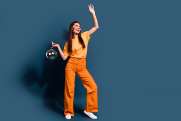 Full length photo of latin girl in orange outfit raised hand up holding shine disco ball partying...