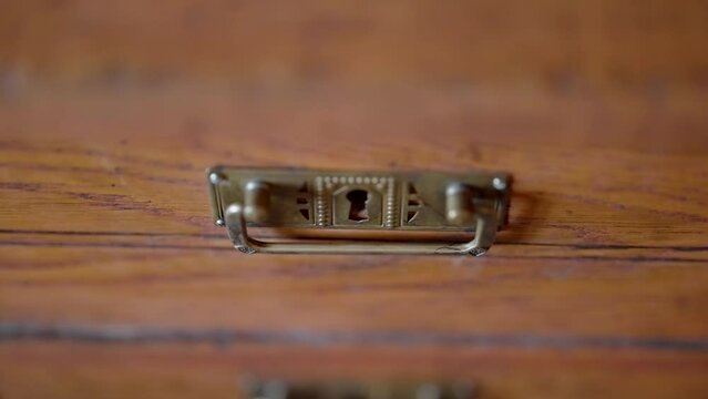 Close up of an antique brass handle on a wooden dresser drawer exemplifying vintage elegance