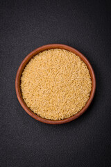 Raw risoni pasta made from durum wheat on a dark concrete background