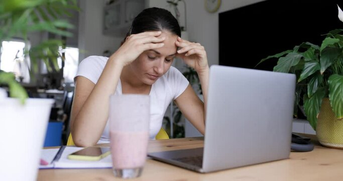 Frustrated businesswoman working on laptop from home