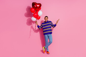 Full length photo of impressed funky man wear striped sweater rising heart balloons bouquet isolated pink color background